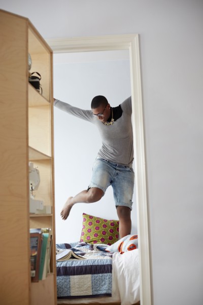 Mixed race woman jumping on bed