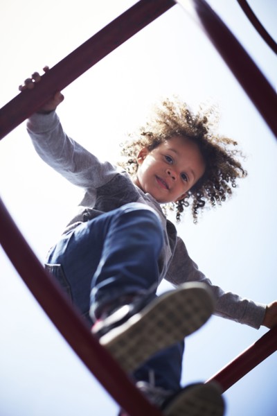 Low angle view of mixed race boy climbing on play structure