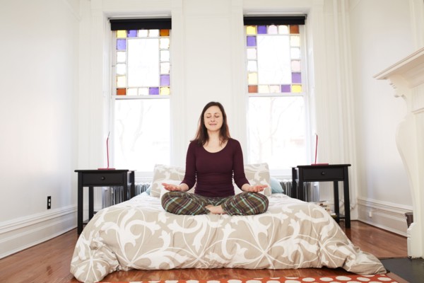 Mixed race woman meditating in bedroom