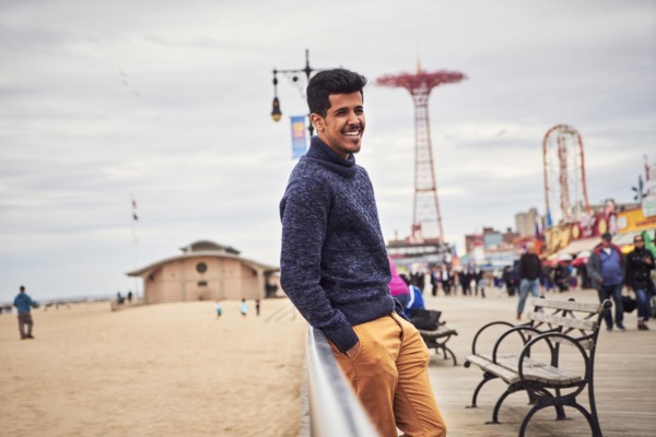Man leaning on boardwalk railing at beach