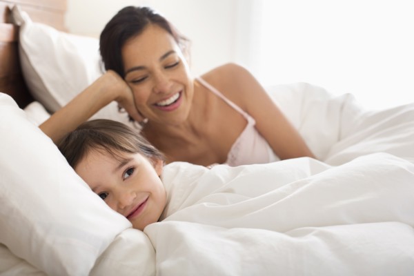 Mother and daughter laying in bed