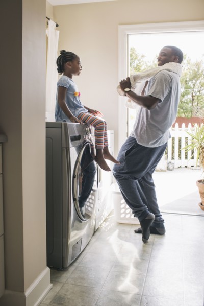 African American father and daughter doing laundry