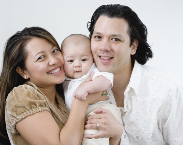 Asian parents hugging baby