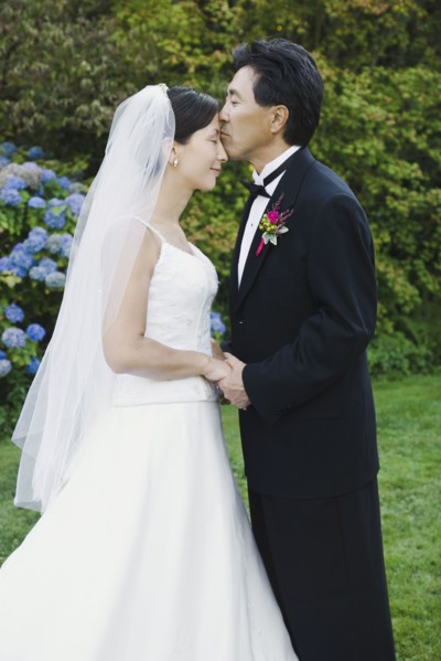 Asian groom kissing bride's forehead