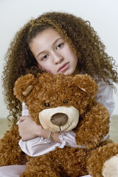 Mixed race girl in nightgown with teddy bear