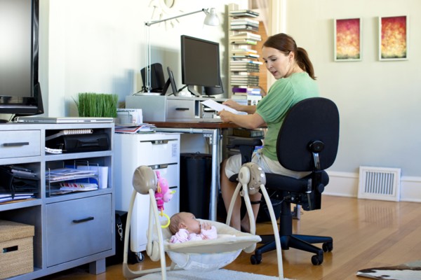 Caucasian mother working in home office with baby next to her