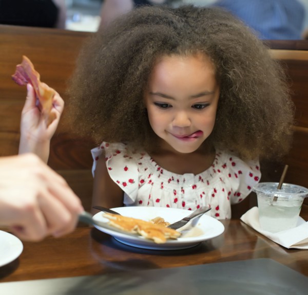 Mixed race girl eating breakfast in restaurant