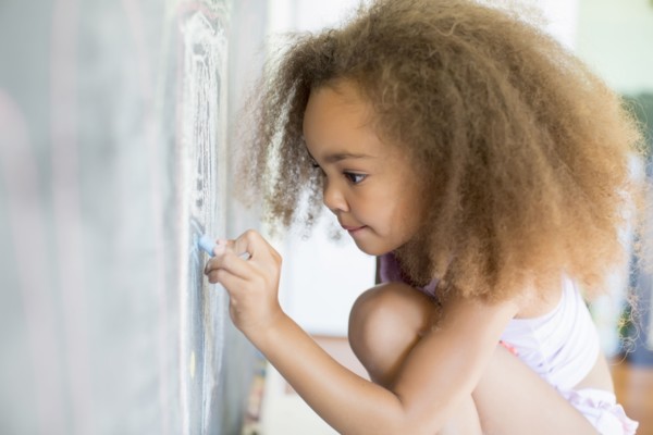 Mixed race girl writing on blackboard