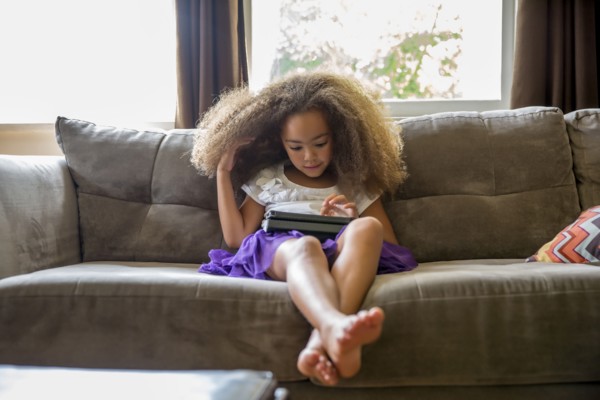 Mixed race girl using digital tablet on sofa