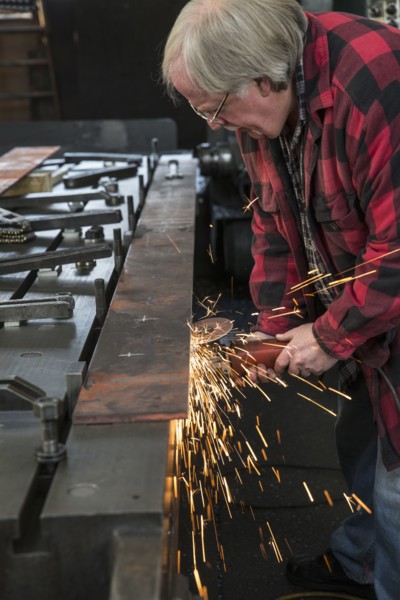 Caucasian man sanding metal in metal shop