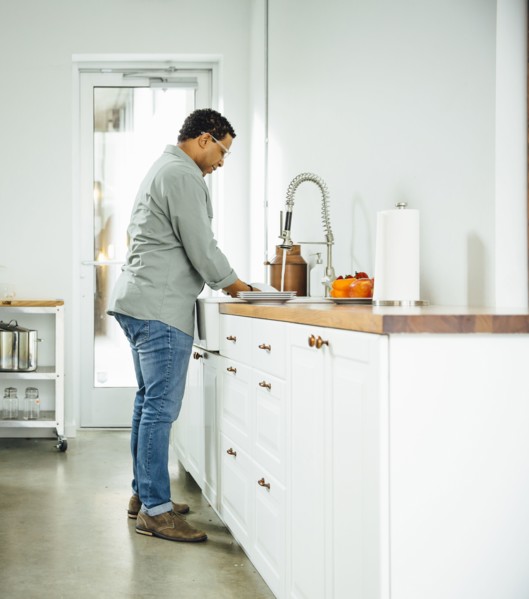 Mixed race man washing dishes in kitchen