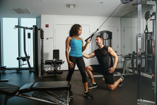 Woman working out with trainer in gymnasium