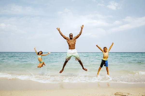 Father and children jumping for joy on beach