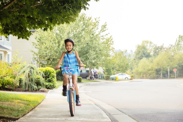 Mixed race girl riding bicycle on sidewalk