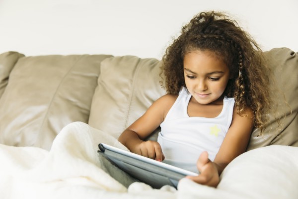 Mixed race girl using digital tablet on sofa