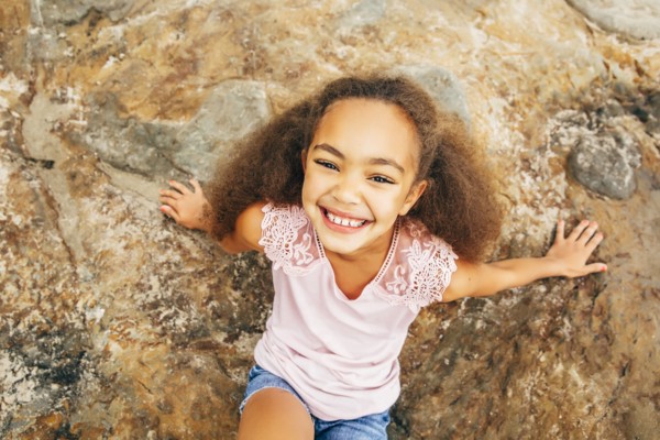 Mixed race girl smiling on rock outdoors