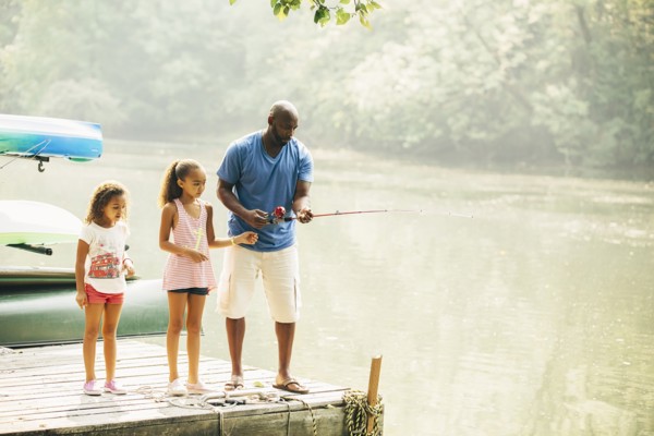Father and daughters fishing in lake