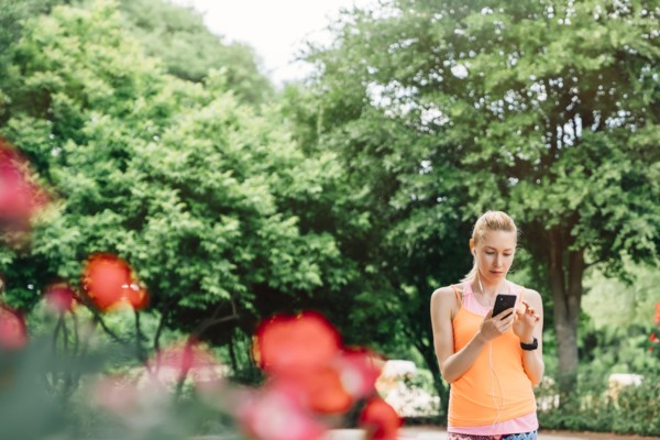 Caucasian woman using cell phone and earbuds outdoors