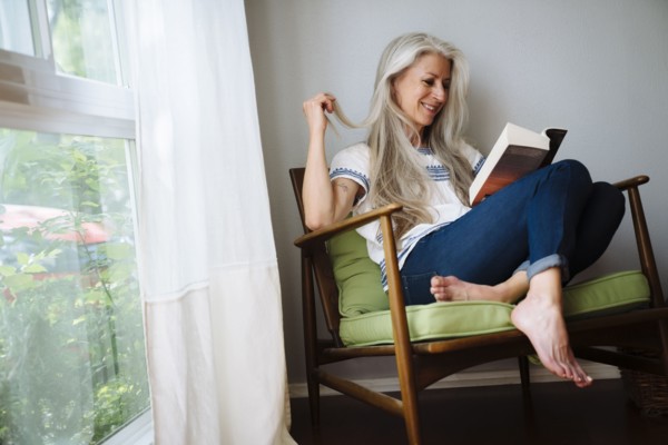 Caucasian woman sitting in armchair reading book