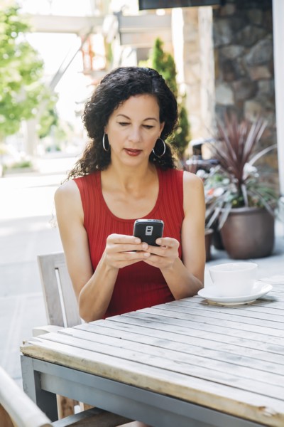 Mixed Race woman texting on cell phone at cafe