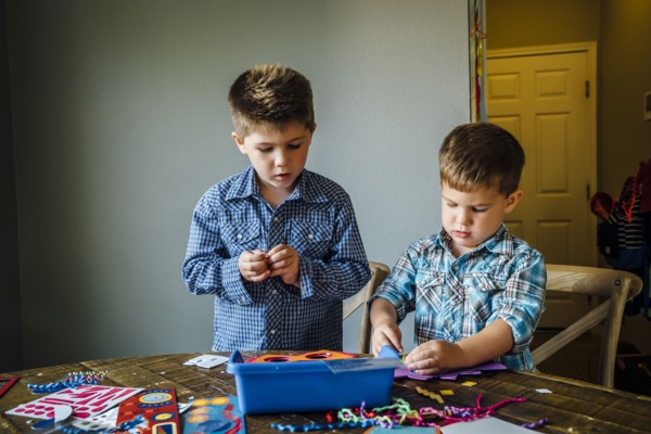 Caucasian boys making masks at table