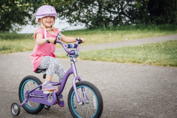 Mixed Race girl riding bicycle with training wheels