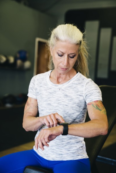 Caucasian woman tapping smart watch in gymnasium