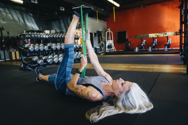 Caucasian woman stretching leg with resistance band