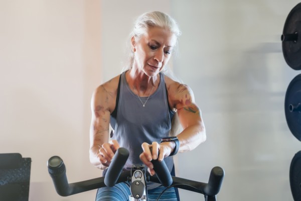 Caucasian woman riding stationary bicycle checking smart watch