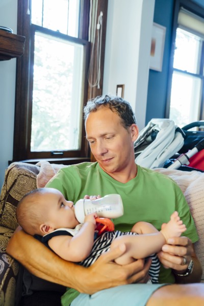 Father holding baby son drinking milk from bottle