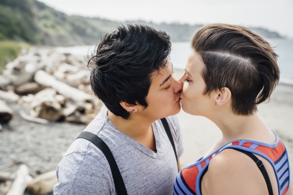 Pregnant lesbian couple kissing on beach