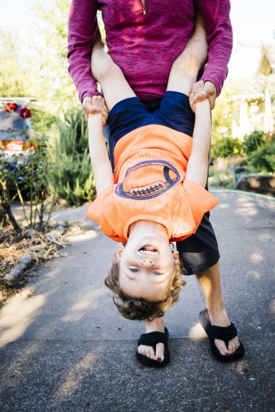 Caucasian mother holding son upside-down