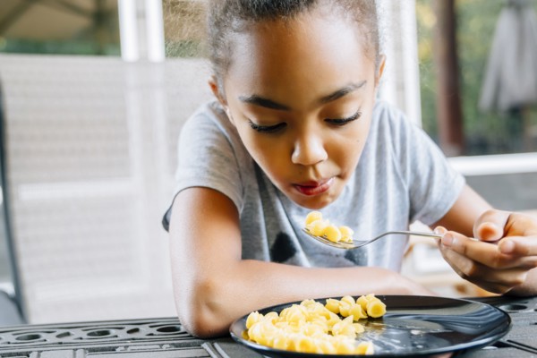 Mixed Race girl eating food with fork