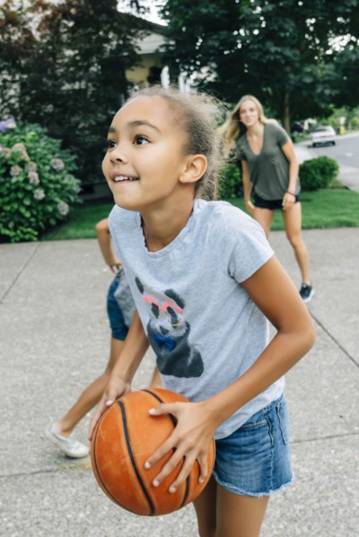 Mother and daughters playing basketball in driveway