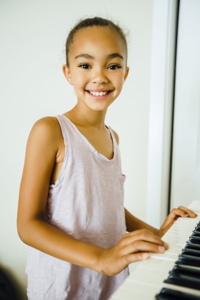 Smiling Mixed Race girl playing music on keyboard