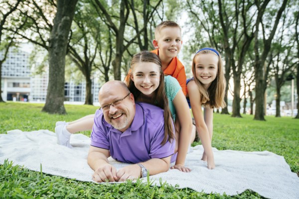 Portrait of Caucasian boy and girls laying on back of father in park