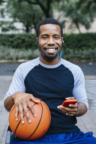 Portrait of Black man listening to earbuds and holding basketball