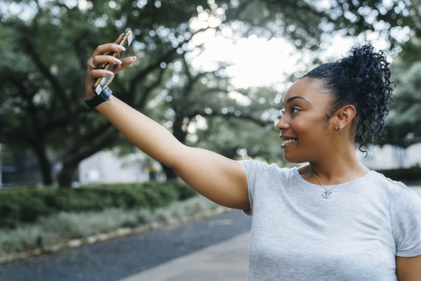 Smiling Black woman posing for cell phone selfie