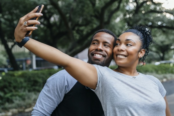 Smiling Black couple posing for cell phone selfie