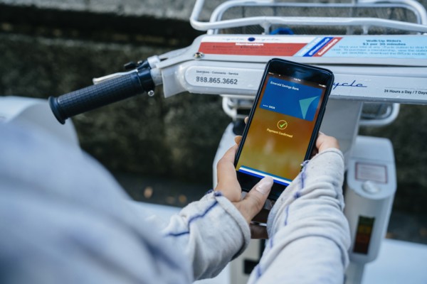 Hands of Black woman paying for bicycle rental with cell phone