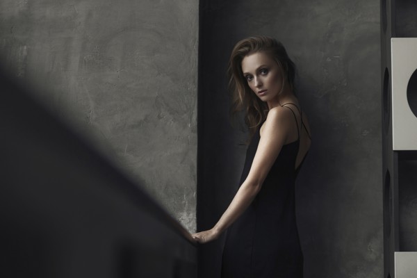 Serious Caucasian woman standing near wall