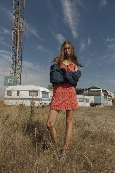 Serious Caucasian woman standing in field near trailers