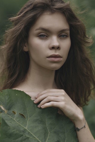 Caucasian woman covering chest with leaf