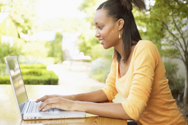 Profile of teenage girl typing on laptop