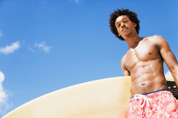 Serious African man holding surfboard