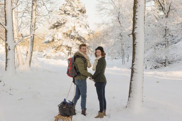 Caucasian couple pulling sled in snow