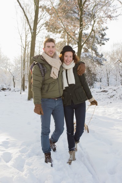 Caucasian couple pulling sled in snow