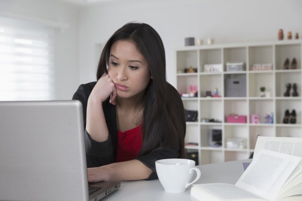 Bored mixed race businesswoman using laptop