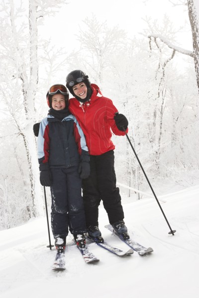 Caucasian mother and daughter cross country skiing in snow