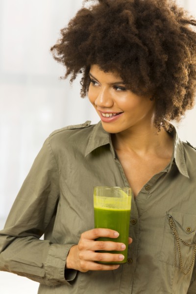 Mixed race woman drinking green smoothie